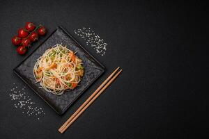 Tasty dish of Asian cuisine with rice noodles, chicken, asparagus, pepper, sesame seeds photo