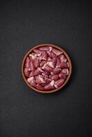 Fresh raw chicken, turkey or duck hearts on a ceramic plate with salt and spices photo