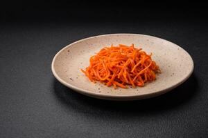 Delicious spicy carrots sliced and cooked in Korean style on a ceramic plate photo