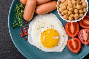 Fried chicken eggs, sausages, cherry tomatoes, chickpeas, spices, salt and herbs photo