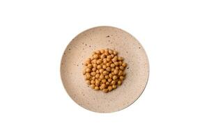 Delicious canned chickpeas in a ceramic plate on a dark concrete background photo