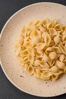 Raw Italian pasta conchiglie from durum wheat with vegetables, salt and spices photo