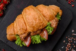 Delicious fresh crispy croissant with chicken or beef meat, lettuce, tomatoes, spices and sauce photo