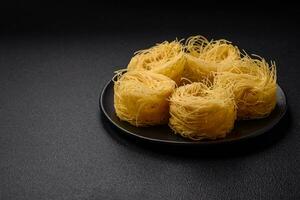 Raw capellini pasta or noodles with salt and spices photo