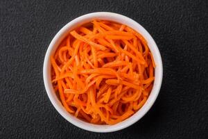 Delicious spicy carrots sliced and cooked in Korean style on a ceramic plate photo