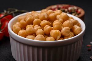 delicioso Enlatado garbanzos en un cerámico plato en un oscuro hormigón antecedentes foto