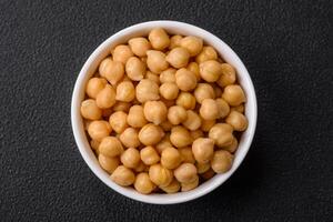 Delicious canned chickpeas in a ceramic plate on a dark concrete background photo