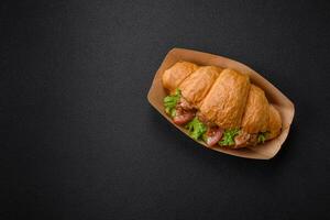 Delicious fresh crispy croissant with chicken or beef meat, lettuce, tomatoes, spices and sauce photo
