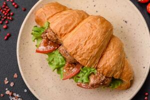 Delicious fresh crispy croissant with chicken or beef meat, lettuce, tomatoes, spices and sauce photo