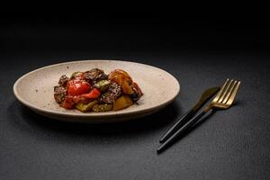 Warm salad with veal, tomatoes, peppers, zucchini, sesame, salt, spices and herbs photo