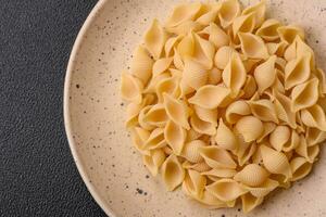 Raw Italian pasta conchiglie from durum wheat with vegetables, salt and spices photo