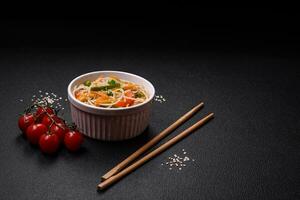 Tasty dish of Asian cuisine with rice noodles, chicken, asparagus, pepper, sesame seeds photo