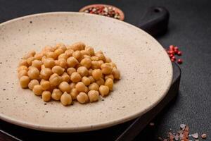 Delicious canned chickpeas in a ceramic plate on a dark concrete background photo