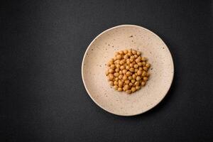 Delicious canned chickpeas in a ceramic plate on a dark concrete background photo