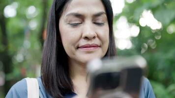 vrouw Holding een telefoon in haar hand- glimlachen op zoek Bij de smartphone scherm video