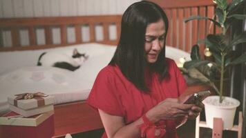 asiático mujer utilizando teléfono inteligente, móvil comunicación a su propio hogar durante vacaciones video