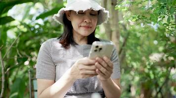 mujer utilizando móvil teléfono en sombreado parque video