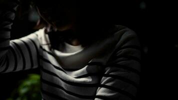 depresso e stressato giovane donna seduta nel il scuro, concetto di negativo emozioni. video