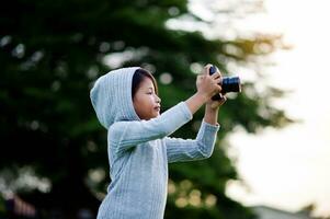 Take pictures with a mirrorless camera. Little girl practicing nature photography little photographer the joy of taking pictures photo