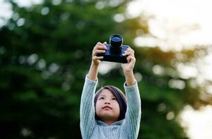 Take pictures with a mirrorless camera. Little girl practicing nature photography little photographer the joy of taking pictures photo