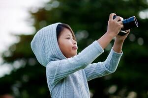 Take pictures with a mirrorless camera. Little girl practicing nature photography little photographer the joy of taking pictures photo