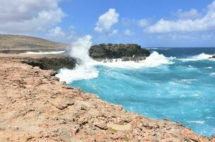 Large Waves Splashing Against the Rock Cliffs in Aruba photo