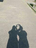 Silhouette of hand made heart shape on black cement background photo