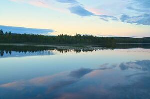 Calm lake in Sweden at blue hour sunset. Clouds reflected in the water. Swimming photo