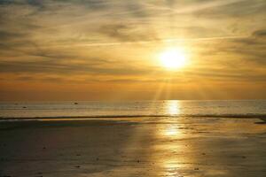 Sunset, illuminated sea. Sandy beach in the foreground. Light waves. Baltic Sea photo