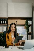 Asian businesswoman working in the office with working notepad, tablet and laptop documents in office photo