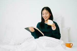 Portrait of Good Healthy Young Asian woman reading book and resting in bed at bedroom.  in morning lifestyle concept photo