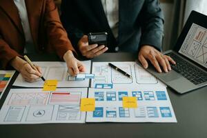UX developer and ui designer brainstorming about mobile app interface wireframe design with customer breif and color code at office. photo