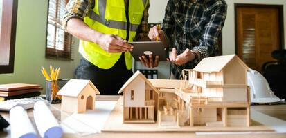 scale model house on table with architects. Two architects making architectural model in office together. to form a new buildin photo