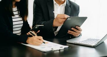 Business documents on office table with smart phone and calculator digital tablet and graph business with social network diagram and two colleagues discussing data working in the office photo