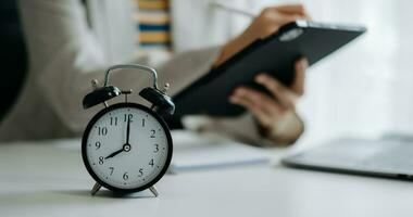 Alarm clock on the desk. Business hand using smartphone, laptop and tablet  working in modern office building or home photo