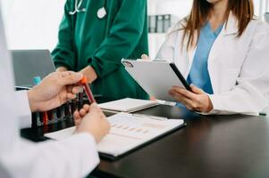 Medical team having a meeting with doctors in white lab coats and surgical scrubs seated at a table discussing a patients working online using computers in the medical industry photo