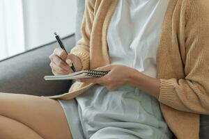 Asian Business woman working from office taking reading and writing notes in note pad photo
