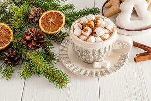 Beautiful cup with New Year knitted pattern with hot cocoa or chocolate drink with marshmallows on white wooden table. concept of cozy Christmas photo
