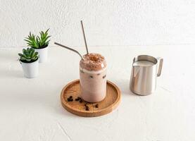 Delicious aromatic freshly brewed coffee in a glass glass in the shape of a beer can with eco straw stands on a wooden tray. white background. photo