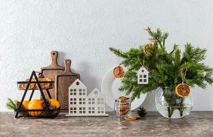 Spruce branches in a white jug decorated with dry orange slices and a stylish basket of fresh oranges fruits on the New Year's countertop. photo