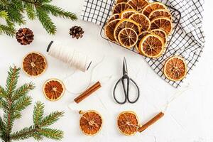 Top view of trellis with slices of dried oranges for home DIY Christmas garland for holiday. scissors, a skein of thread. spruce branches. photo