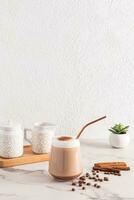 Chic large glass of freshly brewed coffee with foam and ground cinnamon on a marble table. still life. Vertical front view. photo