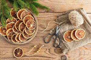 Dry orange slices on a wooden round tray for making your own Christmas garland, Christmas decorations for the home. Top view. Rustic style. photo