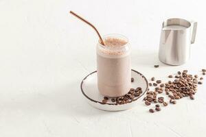 A delicious coffee cappuccino, latte with foam in a modern glass in the form of a beer can stands on a plate among coffee beans. white background photo