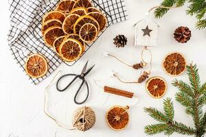 Christmas garland with dried orange slices, wooden house with cones, tray with dried orange slices. Handmade Christmas decorations. Natural decor. photo