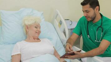 Doctor shows something on his tablet to female patient video