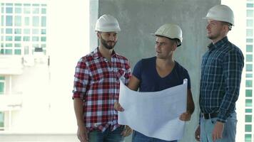 Tres constructores actitud a el edificio debajo construcción video