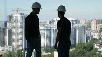dos constructores Mira a el paisaje de alto edificios video