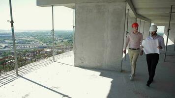 Two male builders walking through the building under construction video