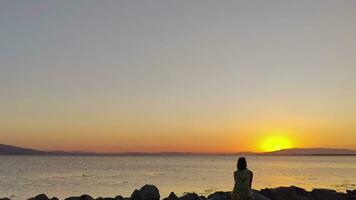 Silhouette von ein Frau suchen beim das Aussicht auf das Strand beim Sonnenuntergang video